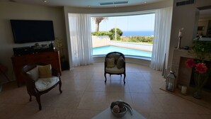 A living room with a television, a fireplace, and a view of the ocean. - Super 3 Bedroom Villa With Amazing Ocean Views (Swieqi)