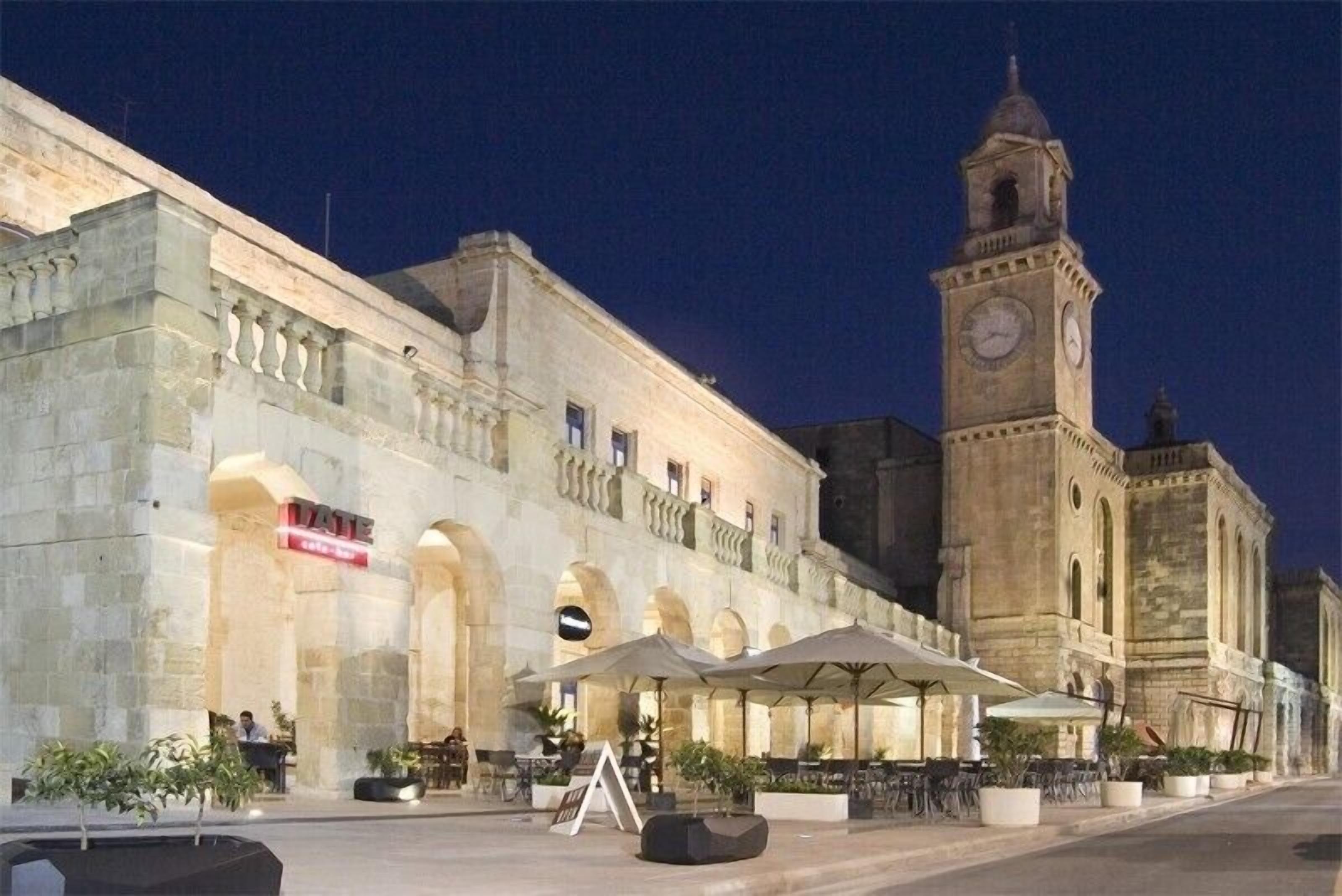Un bâtiment historique doté d’une tour horlogée, d’une terrasse et d’une enseigne indiquant la présence d’un restaurant.