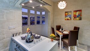 A modern kitchen with a dining area, large windows, and a city view. - Charming Seafront House In Kalkara (Kalkara)