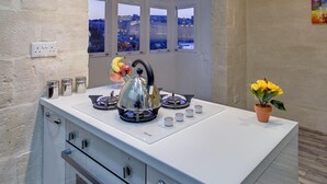A modern kitchen with a built-in oven, a kettle, and a window with a city view. - Charming Seafront House In Kalkara (Kalkara)