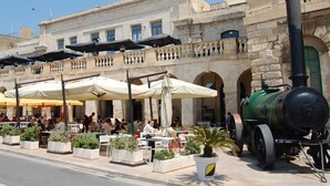 A historic building with outdoor seating and a steam engine. - Charming Seafront House In Kalkara (Kalkara)