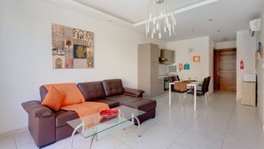 A modern living room with a brown sofa, glass coffee table, and a dining area with a white table and chairs. - Modern Apartment in the Heart of Saint Julian's (St. Julian's)