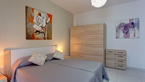A bedroom with a bed, a wardrobe, and two paintings on the wall. - Modern Apartment in the Heart of Saint Julian's (St. Julian's)