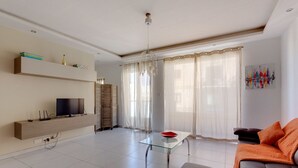 A modern living room with a sofa, a glass coffee table, a TV, and a bookshelf. - Modern Apartment in the Heart of Saint Julian's (St. Julian's)
