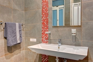 A bathroom with a white sink, a towel rack with a patterned towel, a red and white tiled accent wall, a mirror, and a blue door.