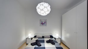 Quarto moderno com uma cama grande, duas mesas de cabeceira com luminárias, um lustre decorativo e um guarda-roupa.