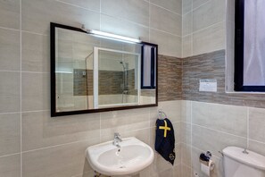 Un baño con un lavamanos blanco, un espejo y un inodoro.