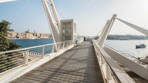 A pedestrian bridge with a view of a city and water. - Modern Apartment With Stunning Seaviews (Sliema)