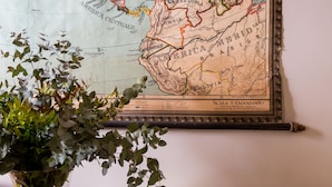 A map on a wall, a yellow sofa, and a glass table with a vase. - Oltrarno Splendid (Florence)