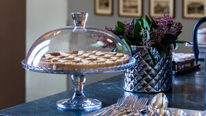 A dessert display with a glass dome cover, a tray of cookies, and a vase with flowers on a table. - Oltrarno Splendid (Florence)