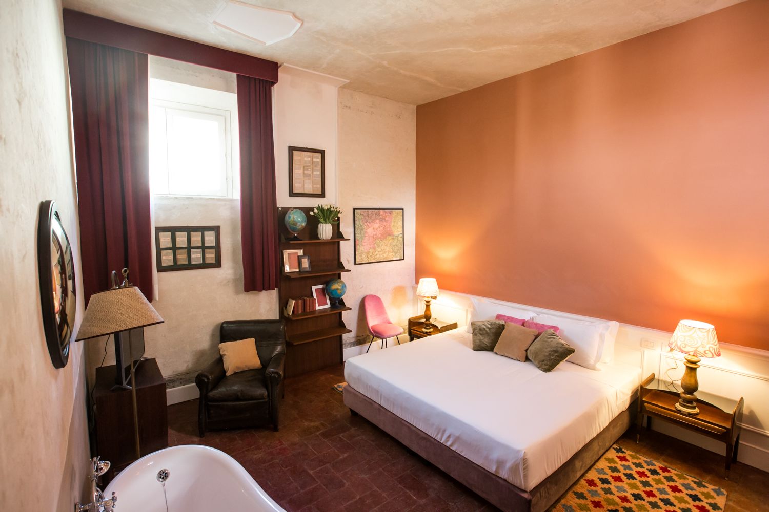 Un dormitorio con una cama grande, un escritorio, una silla, una estantería, un globo terráqueo y un cuadro.