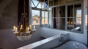 A bathroom with a large window, a bathtub, and a chandelier. - Oltrarno Splendid (Florence)
