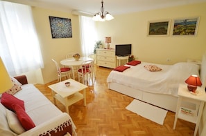 Habitación de hotel con cama, escritorio, silla, mesita y televisor.