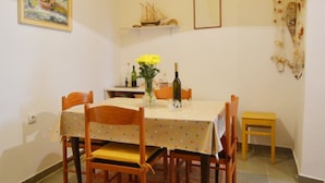 Een eethoek met een tafel voor vier personen, een hanglamp en een klein plankje met decoratieve voorwerpen.