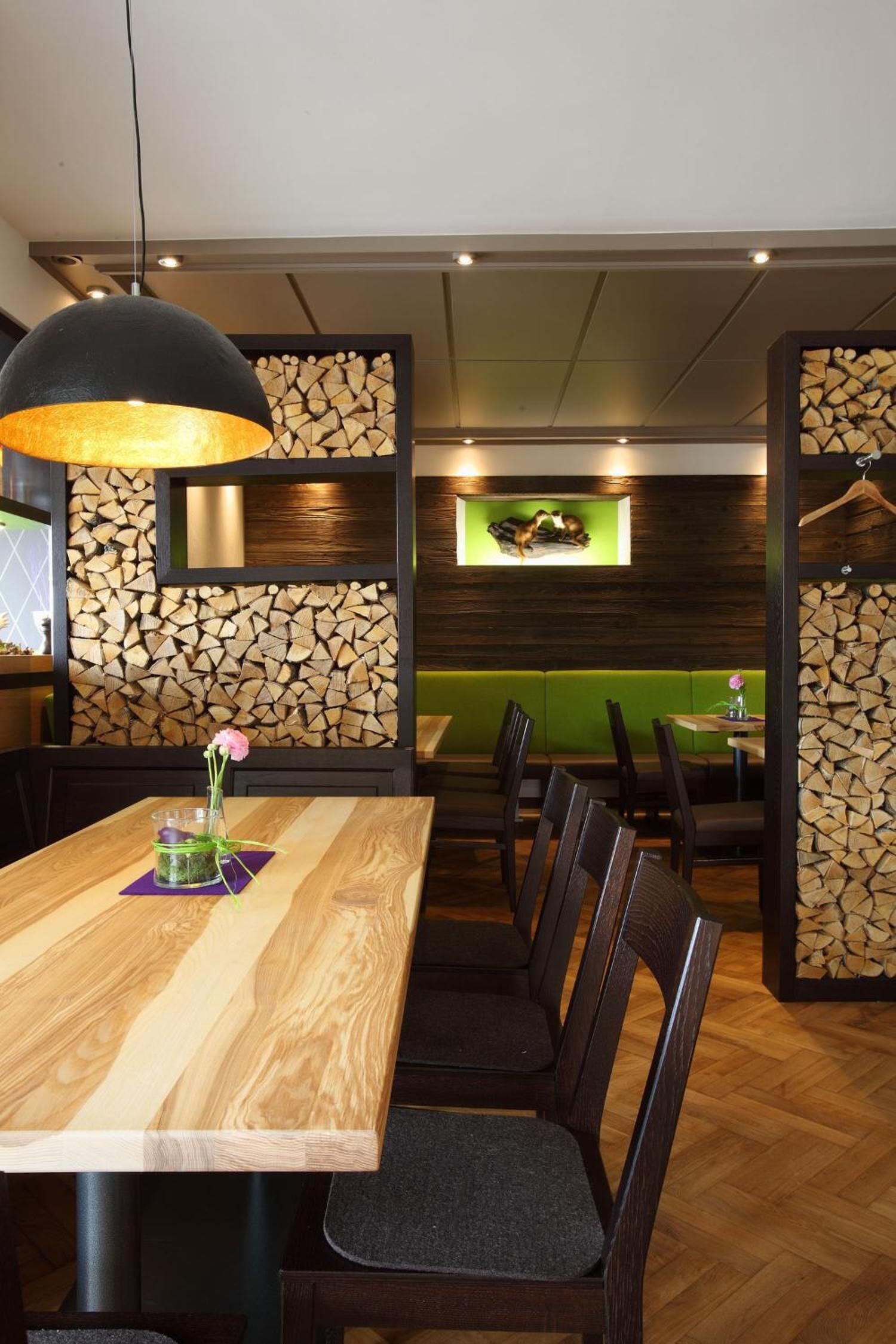 Ein Restaurant mit einem Holztisch, Stühlen und einer hängenden Leuchte.