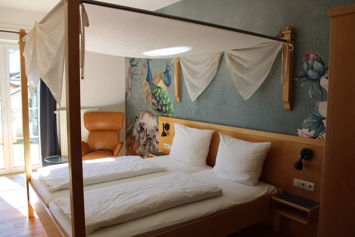 Un lit à baldaquin avec du linge de lit blanc, une tête de lit en bois et une table de chevet avec une lampe.