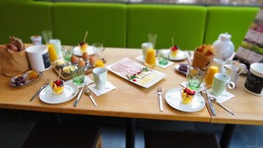Desayuno servido con platos de comida, tazas y cubiertos sobre una mesa de madera.