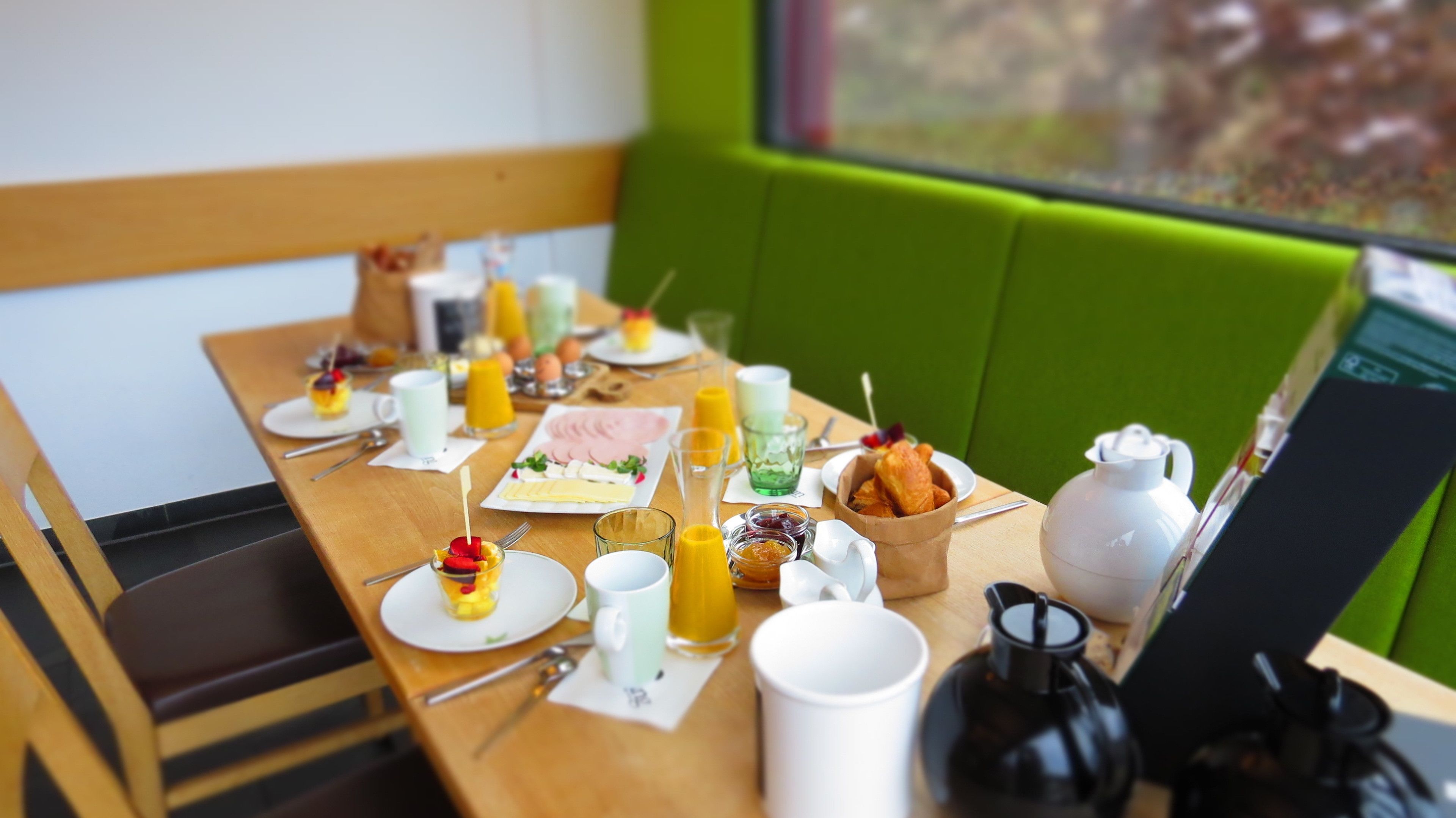 A breakfast table set with plates of food, glasses of juice, and a coffee pot.