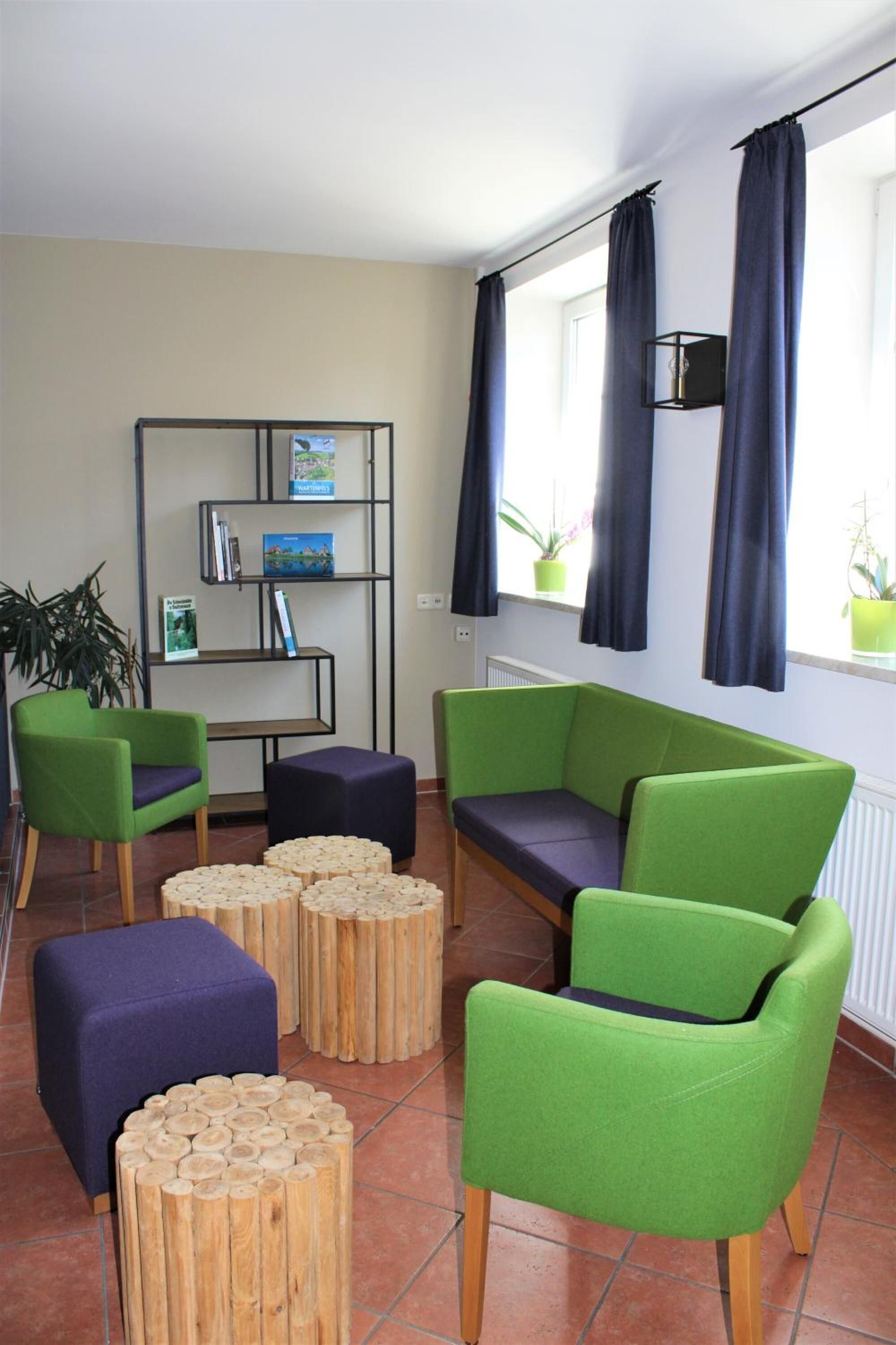A modern living room with green and purple furniture, a wooden coffee table, and a bookshelf.