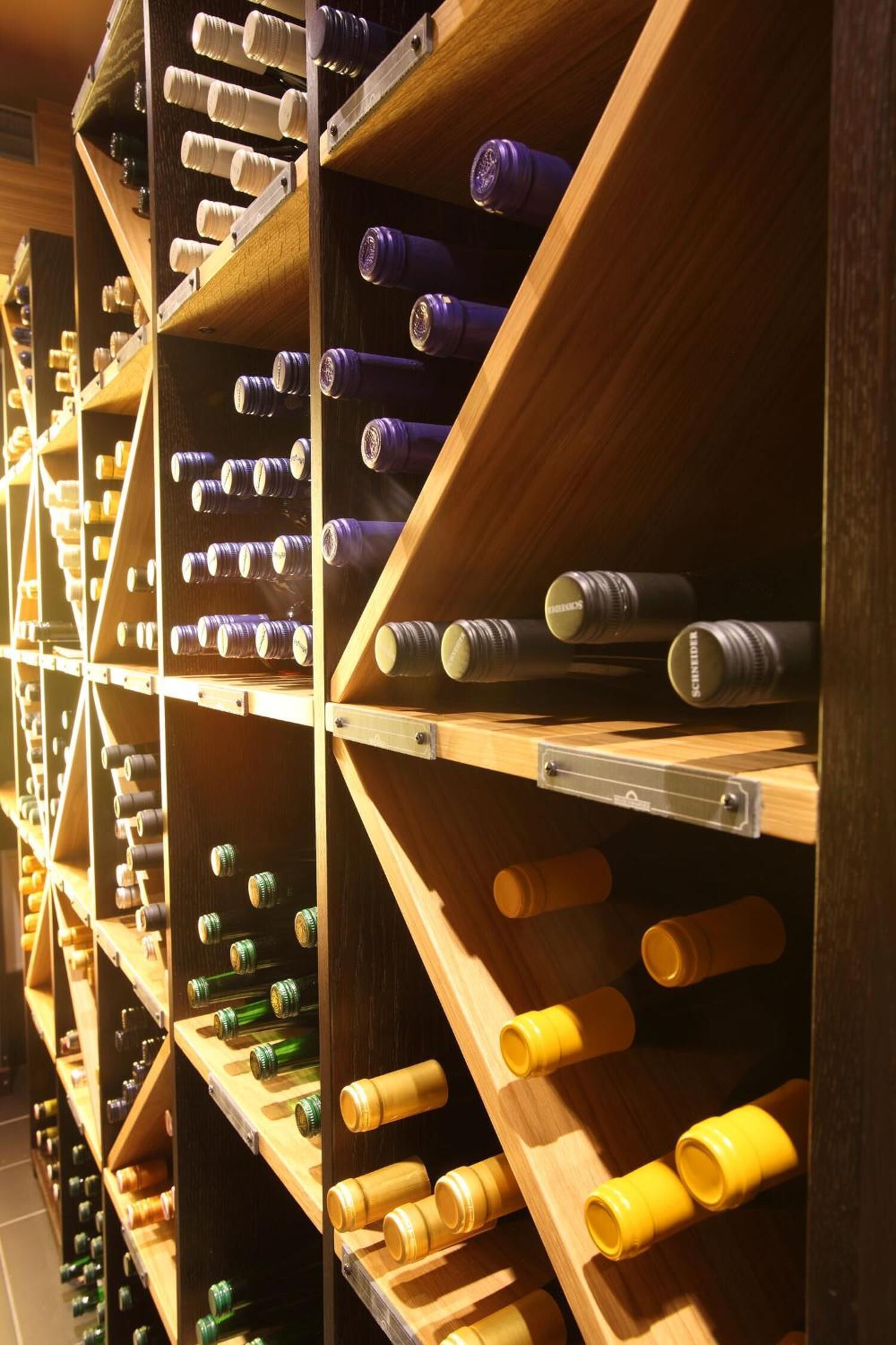 A wine cellar with wooden shelves holding wine bottles.