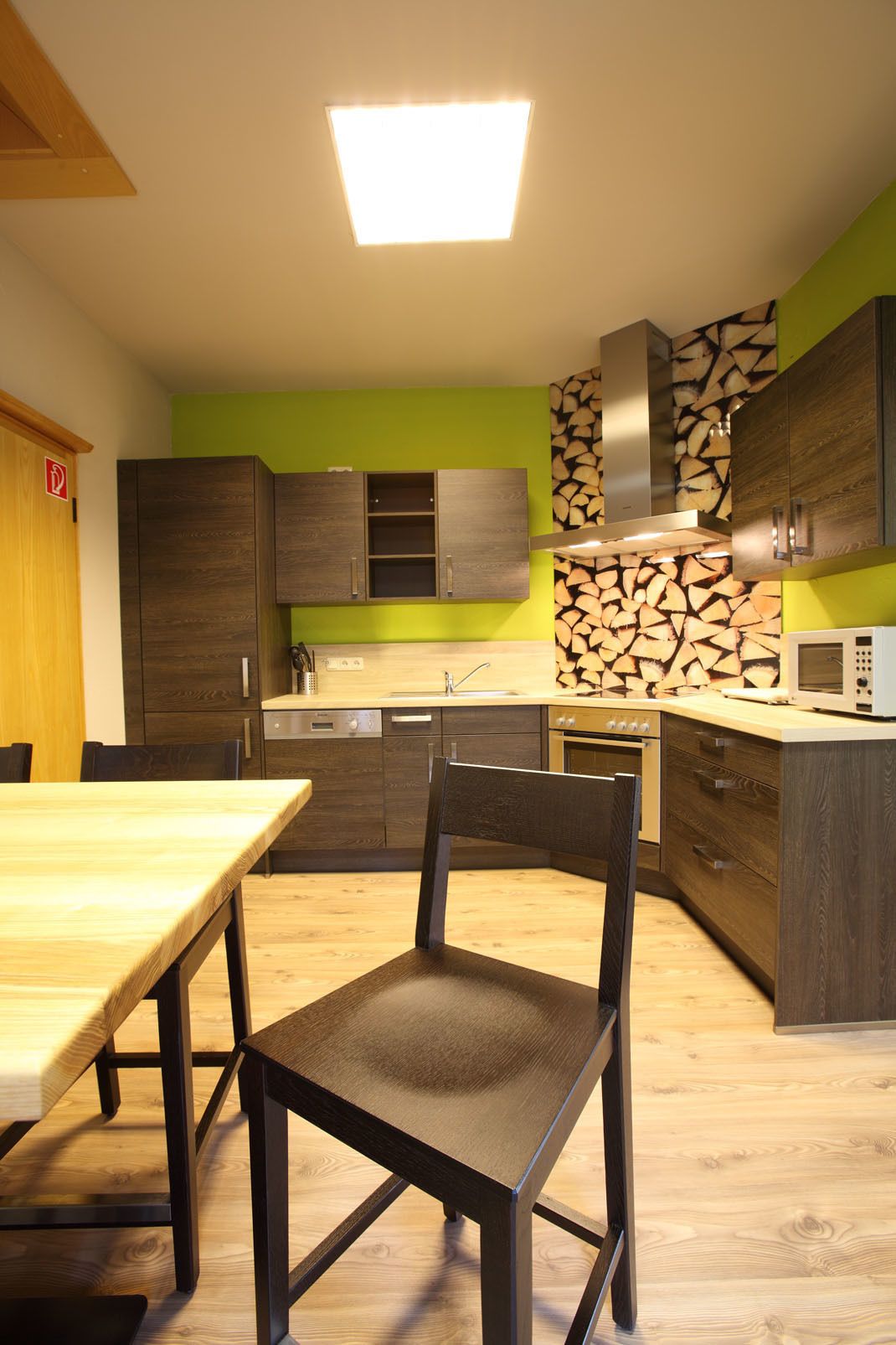 A modern kitchen with wooden cabinets, a central island, and a dining area with a table and chairs.