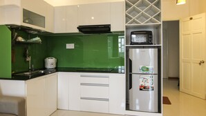 A modern kitchen with white cabinets, a green backsplash, a built-in oven, a microwave, and a refrigerator.