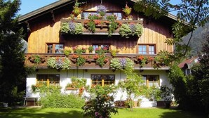 Un chalet traditionnel en bois, doté de plusieurs balcons ornés de plantes et de fleurs en pot.