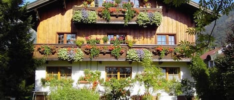 A traditional wooden chalet with multiple balconies adorned with potted plants and flowers.