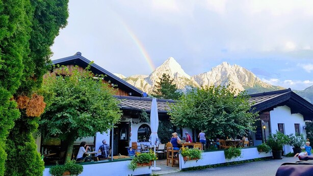 Un restaurant doté d’une terrasse, entouré de verdure et offrant une vue sur les montagnes.