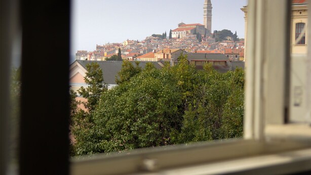 A cityscape with a prominent tower and dense urban buildings. - Art Apartment (Rovinj)