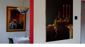 A room with a mirror, a table with a lamp, and a painting of a still life with fruit and candles. - Art Apartment (Rovinj)