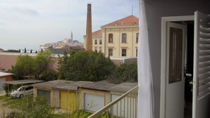 A residential area with a view of a historic building with a tall chimney, a yellow building with a red roof, and a white building with a balcony. - Art Apartment (Rovinj)