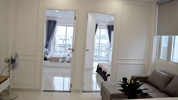 A modern hotel room with a balcony, a sofa, and a fan. - Smiley Apartment 8 (Ho Chi Minh City)
