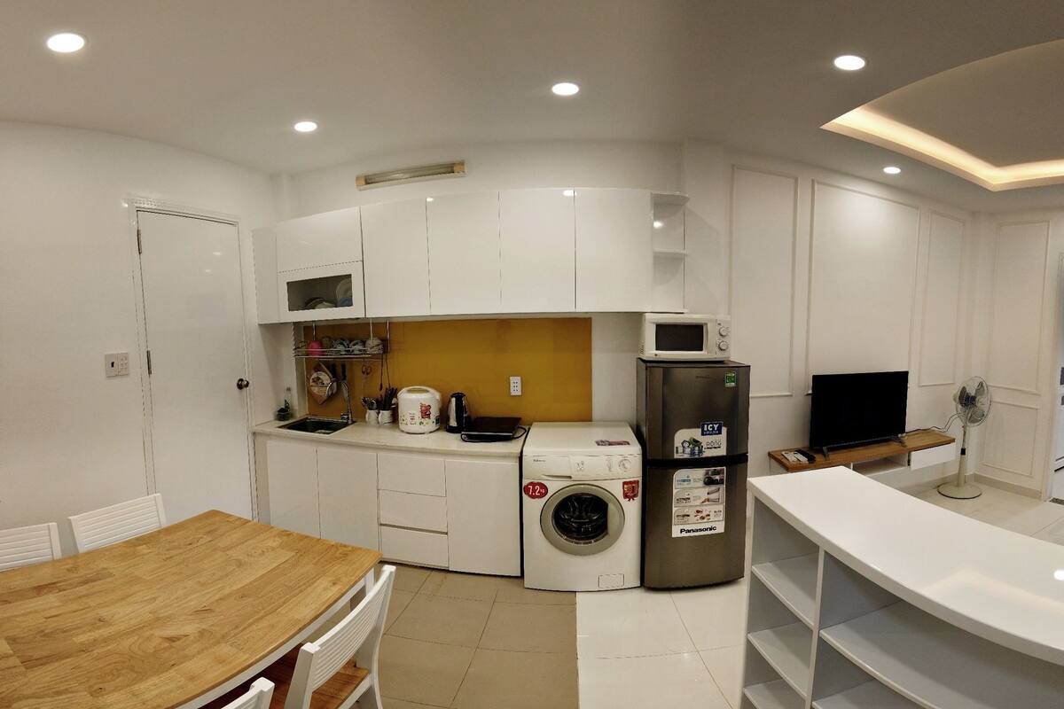 A compact kitchen with a washing machine, microwave, and refrigerator.