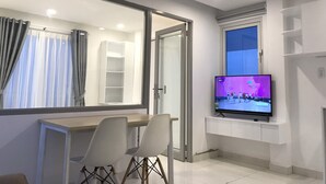 A modern living room with a TV, a dining area with chairs, a large mirror, and a window. - Smiley Apartment 8 (Ho Chi Minh City)