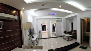 A modern living room with a dining area, a ceiling fan, and a view into the adjacent bedroom. - Smiley Apartment 8 (Ho Chi Minh City)