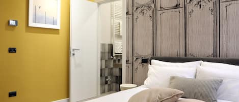 A hotel room with a bed, pillows, a wardrobe, and a mirror.