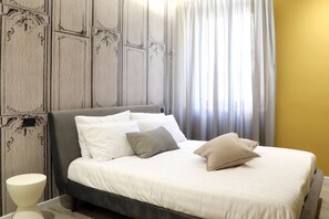 Un lit bien fait, avec des oreillers blancs et beiges, une tête de lit grise et un design moderne.