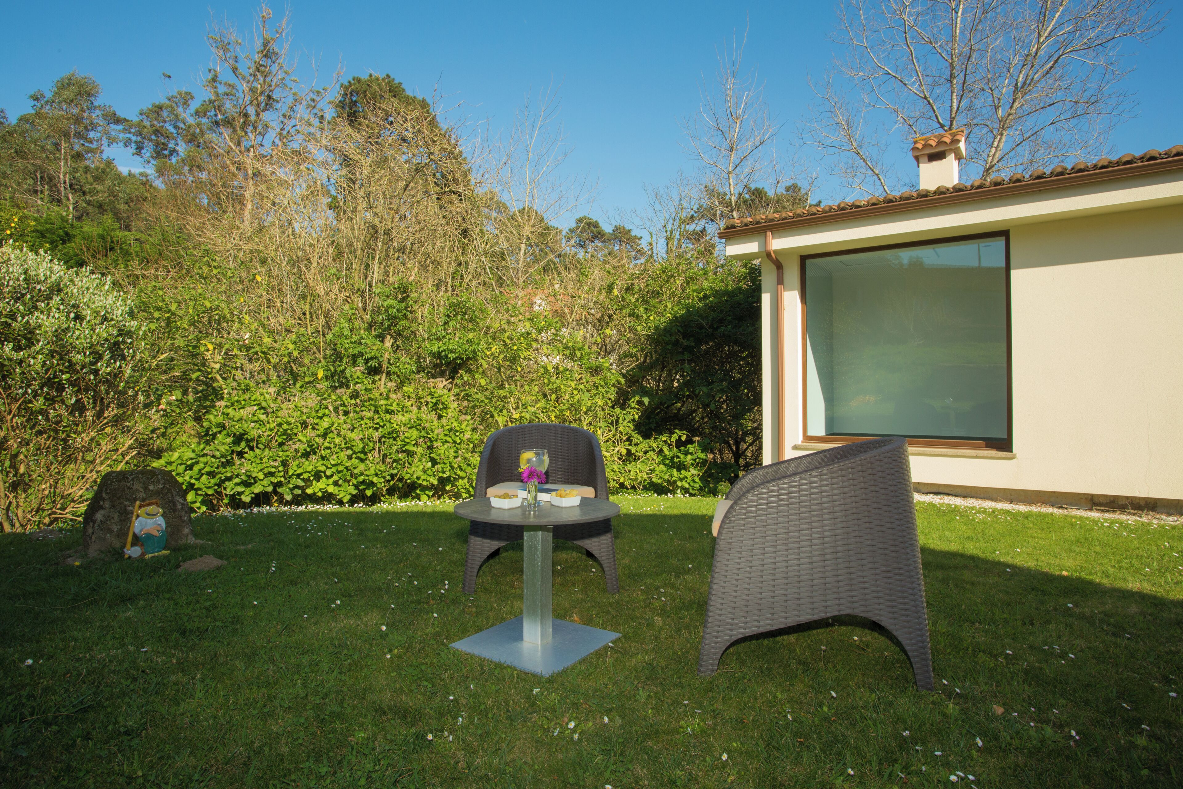 Une terrasse avec deux fauteuils en osier, une petite table et une pierre décorative.