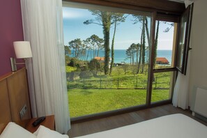 A bedroom with a large window, a bed, a bedside table, and a lamp. - Hotel Alén do mar (Fisterra)