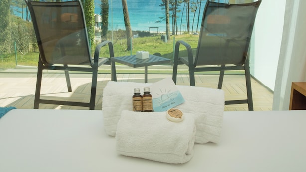 A room with a view of the ocean, two chairs, a table with toiletries, and a towel. - Hotel Alén do mar (Fisterra)