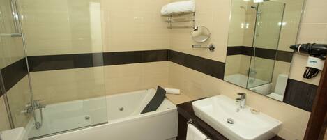 A modern bathroom with a glass-enclosed shower, a white bathtub, a sink, and a mirror.