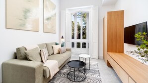 Uma sala de estar moderna com um sofá, uma mesa de centro, uma TV e um tapete estampado.