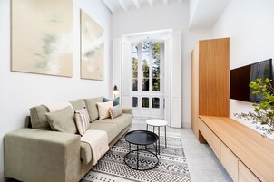 Una sala de estar moderna con sofá, una mesa de centro, televisor y alfombra estampada.