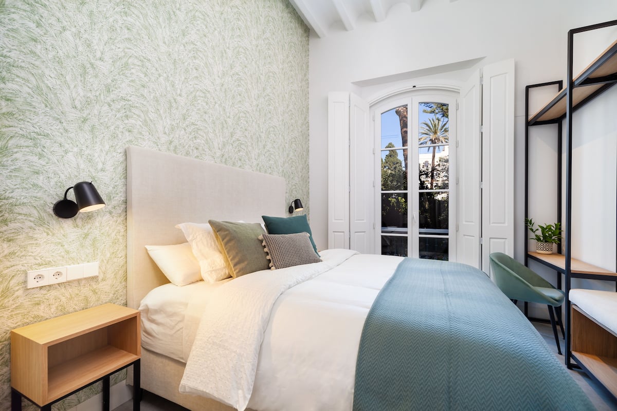 A bedroom with a bed, bedside tables, a window, and a desk.