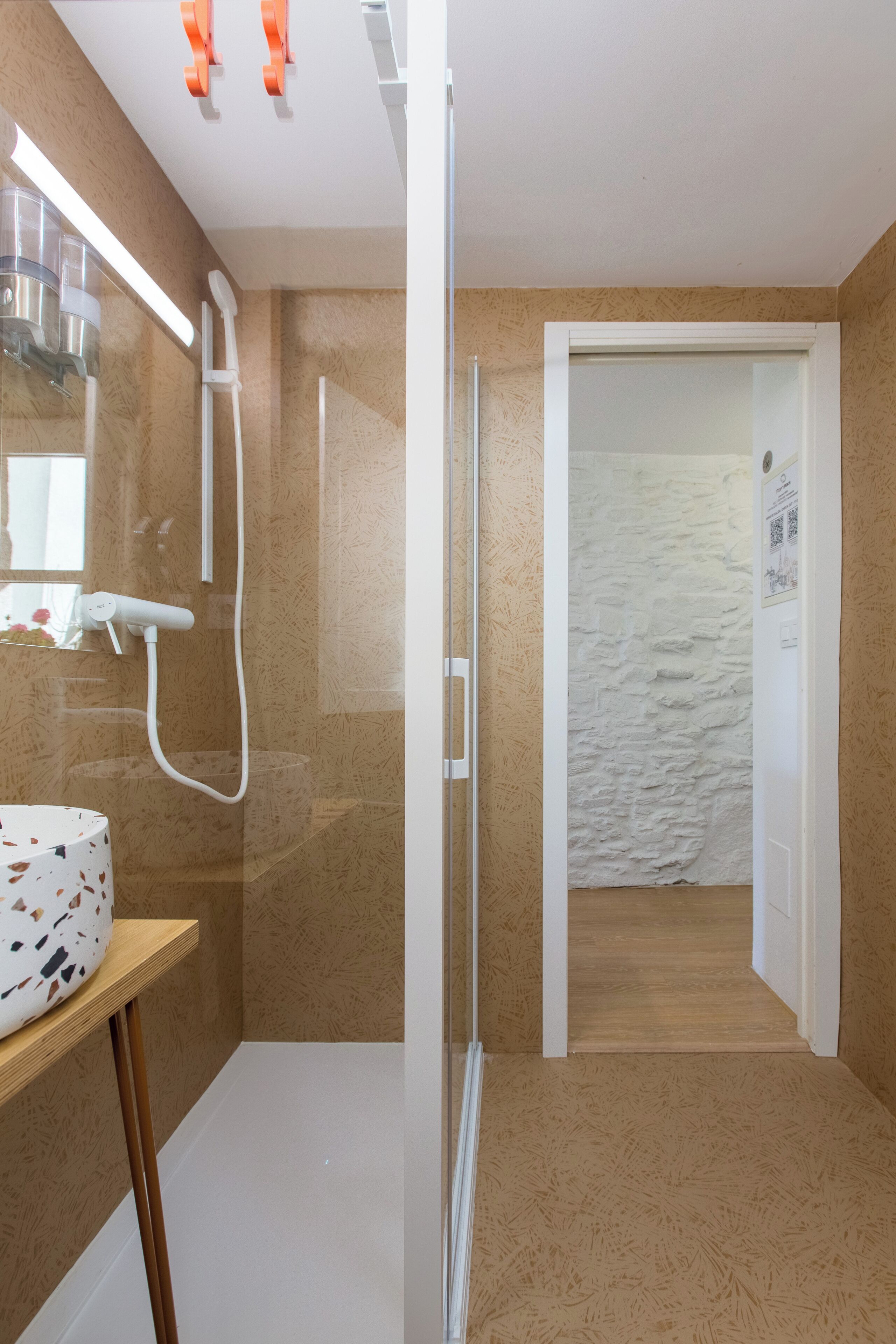 Un baño con ducha, espejo y lavamanos con lavabo estampado.