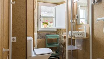 A bathroom with a toilet, shower, and sink.