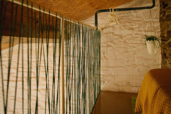 A room with a wooden ceiling, a white brick wall, and a hanging plant. - roomPEDRA Apartamentos Turísticos (Santiago de Compostela)