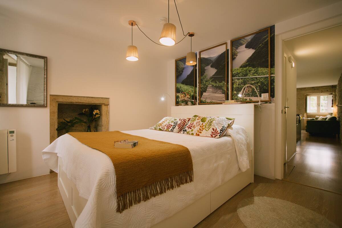 Une chambre à coucher avec un lit, un miroir, une cheminée et des œuvres d’art murales.
