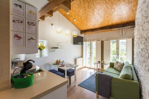 A modern kitchen with a dining area, a green sofa, and a view of the outdoors.